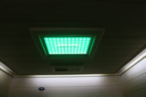 A green chromotherapy light at the top of an infrared sauna