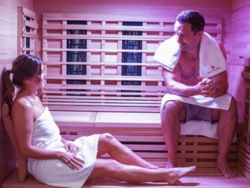 A young man and woman sitting and relaxing in an infrared sauna with candles.