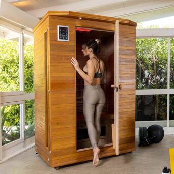 woman in yoga pants stepping into an Enrich infrared sauna