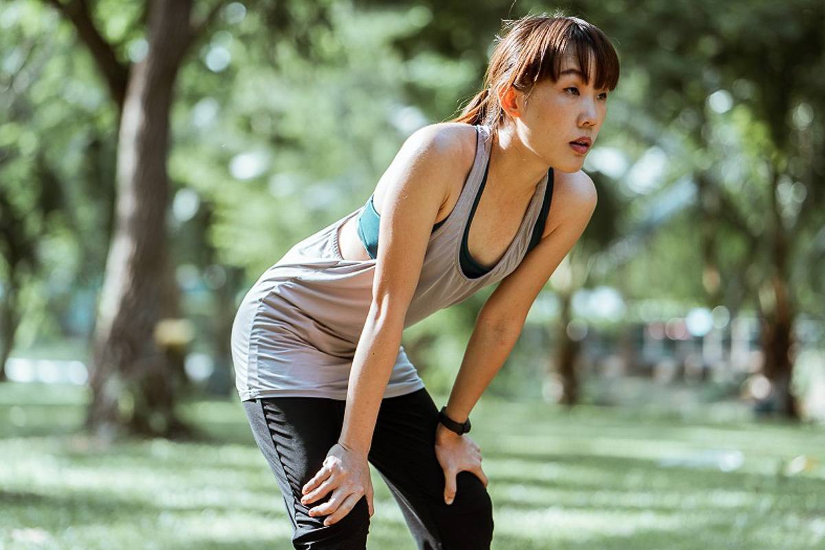woman with hand on her knees taking a break while exercising