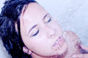 young woman with clear skin splashing water on face